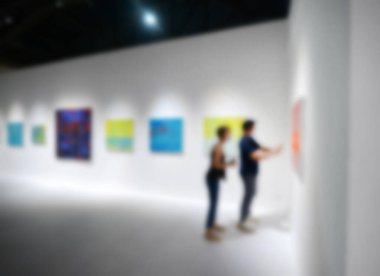 Sanat sergisi galerisindeki beyaz duvardaki resimlere bakıyorlar. Bulanık arkaplan.