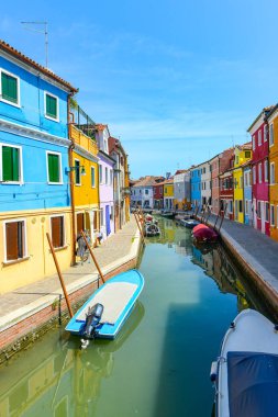BURANO ISLAND, VENICE, ITALY - JULY 4, 2022: Tourists among the sovereign shops and restaurants on the main street of burano Island,  Colorful houses on the canal. Famous travel destination.