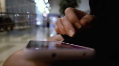 Alışveriş merkezinde akıllı telefonla video oyunu oynayan kadınların ellerini kapat.