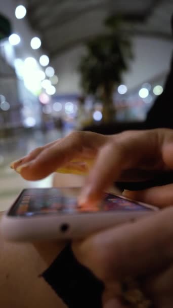 Gros plan des mains féminines jouant au jeu vidéo sur smartphone dans le centre commercial — Video