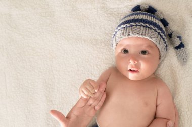 Yatakta şapkalı, şaşırmış bir yüzü olan Latin bebek.