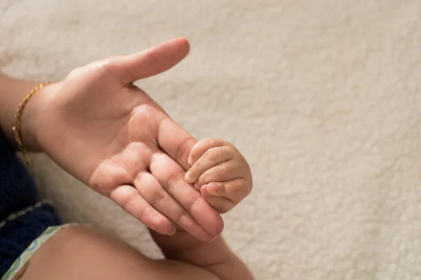 Closeup of Latin Mother holding hand of baby happy at bed — Stock Photo, Image