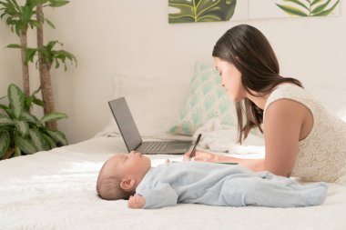 Latin anne bebeğinin yanına yazıyor.