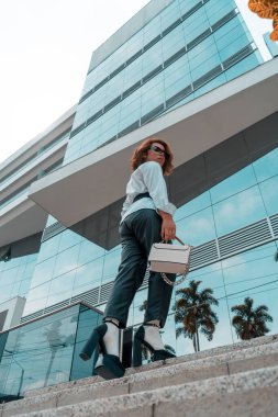 Non-binary executive young of LGBTQ community walking on stairs front of a building