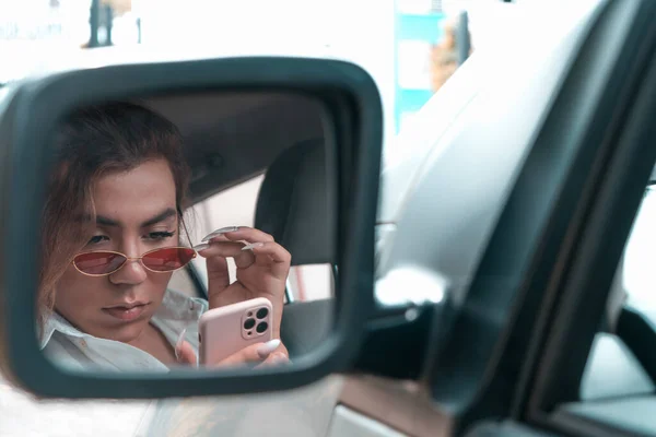 Androgynous young looking surprised your phone at car in the rear view mirror — Photo