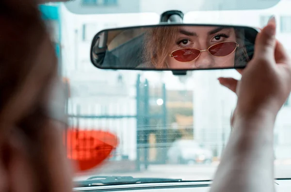 Non-binary young driving a car looking in the rear view mirror — Photo