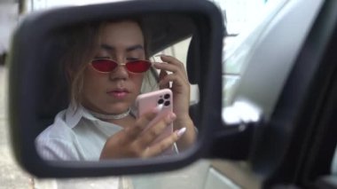 Dikiz aynasından telefonuna bakan ikiz olmayan genç.