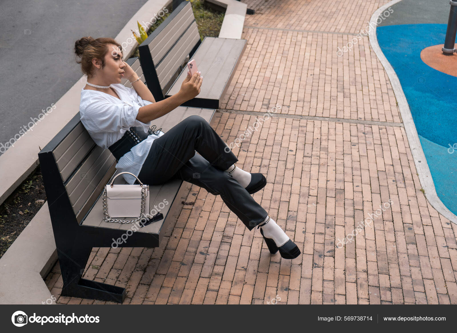 Androgynous vain man taking selfie leaning on black gate in the street