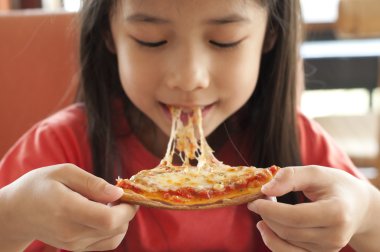 küçük Asyalı kız zevk pizza yemek.