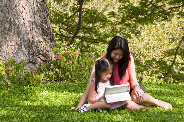 küçük Asyalı kız ve anne tablet pc Park zevk.