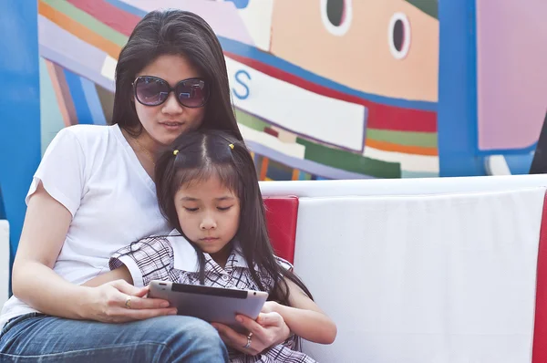 Pouco menina asiática e mãe usando tablet PC no shopping . — Fotografia de Stock