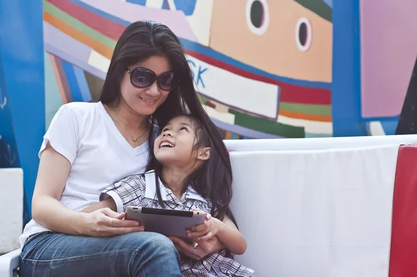 küçük Asyalı kız ve anne kullanarak tablet pc alışveriş merkezi.