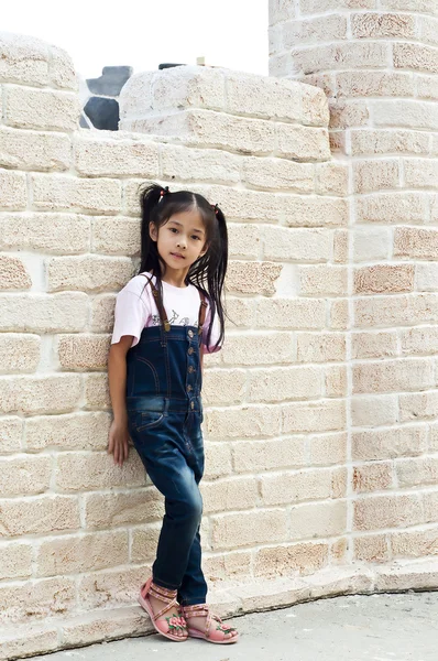 küçük Asyalı kız tuğla arka plan ile poz.