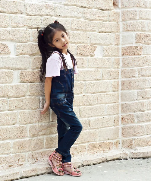 küçük Asyalı kız tuğla arka plan ile poz.