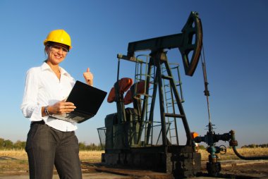 bir petrol sahası içinde gülümseyen kadın mühendis