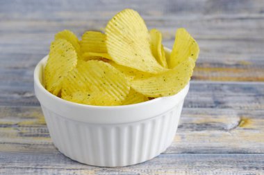 Ekşi kremalı çıtır patates cipsi ve ahşap arka planda soğan..