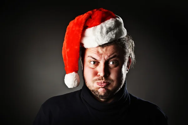 Portrait of man blowing out cheeks and wearing Santa hat — Stock Photo, Image