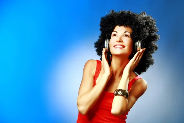 Hermosa mujer sonriente con cabello afro escuchar música con auriculares — Foto de Stock