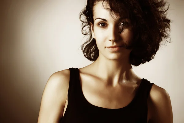 Portrait of beautiful brunette woman with uncombed hair wearing simple black vest — Stock Photo, Image