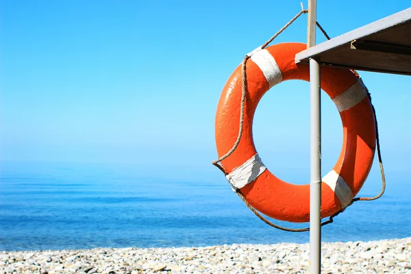 Bóia vermelha pendurada na torre de resgate na praia de seixos. Conceito de segurança — Fotografia de Stock