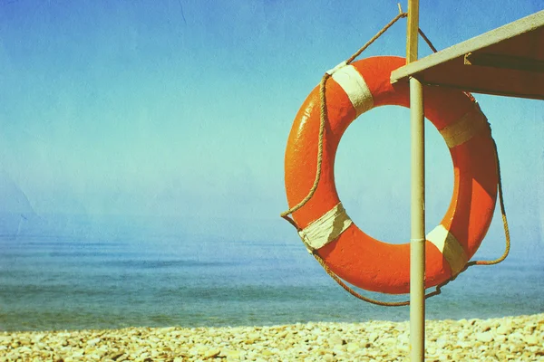 小石のビーチで救助タワーに掛かっている赤いブイ。安全コンセプト — ストック写真