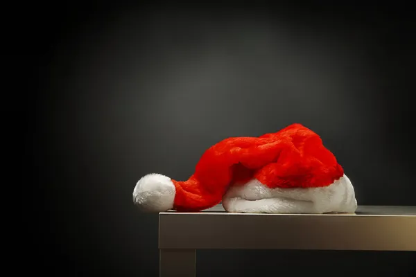 Santa hat laying on table against black background — Stock Photo, Image
