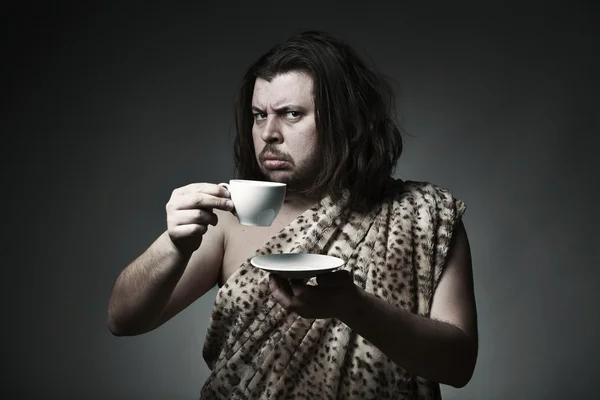 Savage man in skin of beast drink tea or coffee — Stock Photo, Image