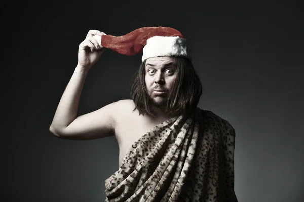 Wild man in leopard skin wear Santa Claus hat. — Stock Photo, Image