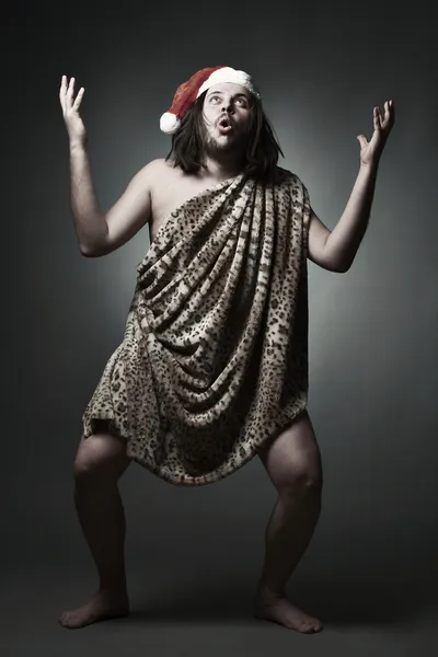 Wild man in leopard skin wear Santa Claus hat. — Stock Photo, Image