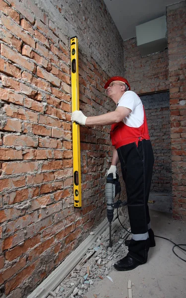 Constructeur de maison en uniforme avec un niveau et un plugger — Photo