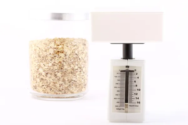 Concepto dietético: balance y copos de avena en un frasco de vidrio aislado o — Foto de Stock