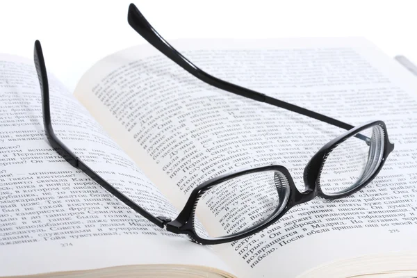 Spectacles lying on the opened book Stock Image