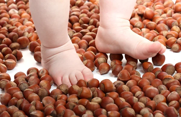 Scaterring nuts and baby's feets — Stock Photo, Image