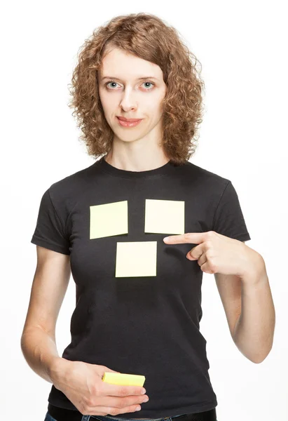 Junge Frau zeigt auf leere Aufkleber auf ihrem T-Shirt (Sie können Ihren Text darauf hinzufügen) — Stockfoto