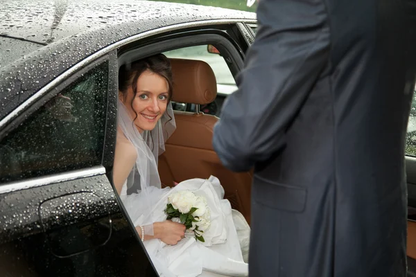 Jonge charmante bruid op zoek uit een auto — Stockfoto