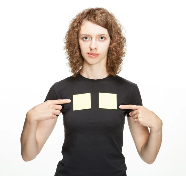 Junge Frau zeigt auf leere Aufkleber auf ihrem T-Shirt (Sie können Ihren Text darauf hinzufügen) — Stockfoto