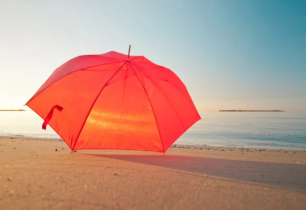 Rött paraply på lugn morgon havsstranden — Stockfoto