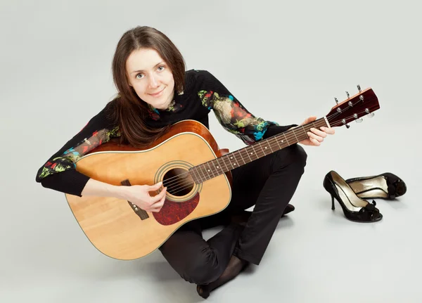 매력적인 갈색 머리 여자는 바닥에 앉아 기타 연주 — 스톡 사진