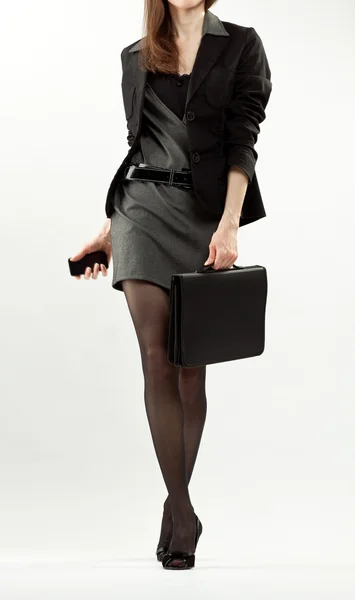 Elegante mujer de negocios caminando con un teléfono celular y maletín — Foto de Stock