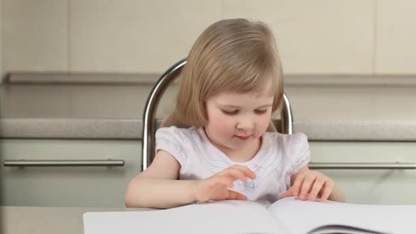 Милая маленькая девочка сидит за столом — стоковое видео