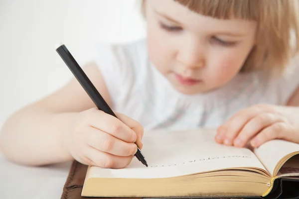 Attentive little girl writing letters — Stock Photo, Image