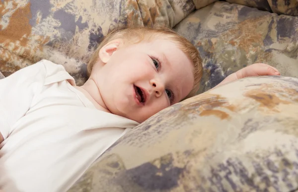 Sorridente bambina sdraiata su un divano a casa — Foto Stock