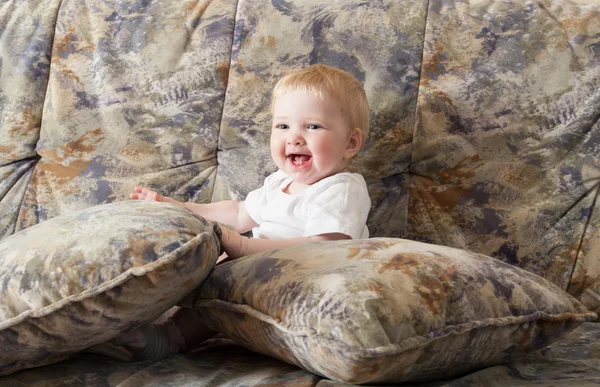 Happy baby girl sitting on a sofa — Stock Photo, Image