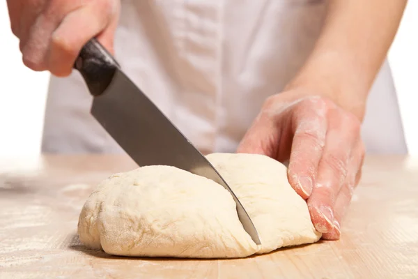 Woman hands cut dough on wooden table — Stock Photo, Image