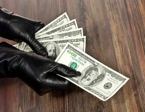 Человеческие руки в черных перчатках с долларами — стоковое фото
