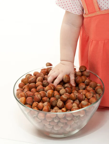 The baby girl is playing with hazelnuts — Stock Photo, Image