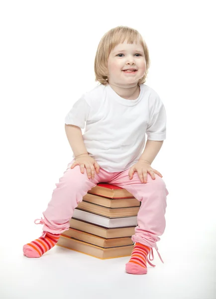 Sorridente bambina è seduto sui libri — Foto Stock