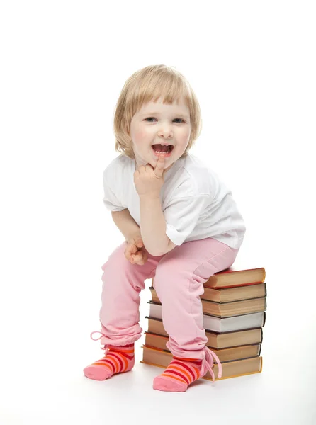 A menina está sentada na pilha de livros — Fotografia de Stock