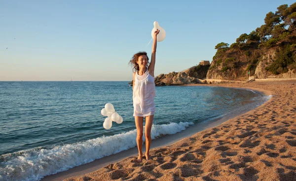 Feliz sorrindo menina morena com balões brancos na praia ensolarada — Fotografia de Stock