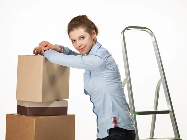 Smiling young woman near a pile of boxes — Stock Photo, Image